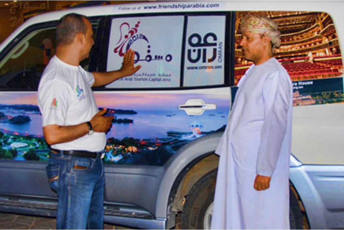 Ali showing Yahya Al Kiyumi the Oman images on the cars 