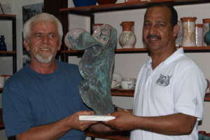 Costis is giving Ali an artistic piece that he made